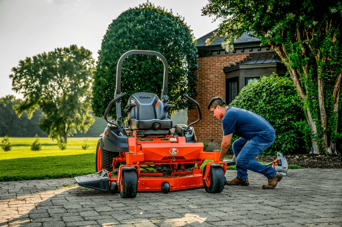 man next to kubota zero turn mower